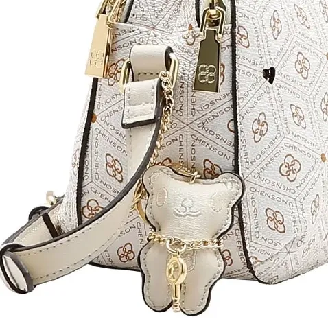Close lateral bolsa transversal Chenson off white com chaveiro ursinho e detalhes dourados.